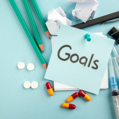 top-view-goals-written-note-with-pills-injections-pencils-blue-background-pandemic-hospital-lab-virus-pill-health-covid-science-color